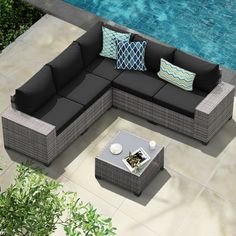 an outdoor sectional sofa with pillows next to a swimming pool