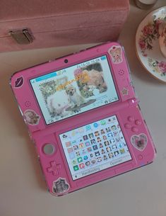 a pink laptop computer sitting on top of a table next to a cup and saucer