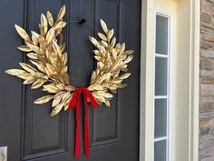 a wreath on the front door of a house with red ribbon hanging from it's side