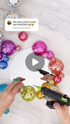 someone is using a circular mirror to make mosaics with colored glass balls on the table