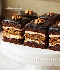 four pieces of cake on a plate with walnuts in the middle and chocolate frosting