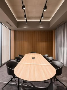 an empty conference room with black chairs and a wooden table in front of large windows