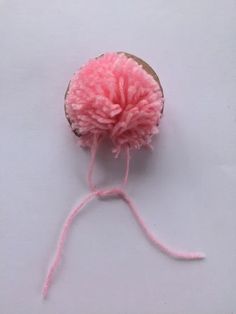 a pink ball of yarn sitting on top of a white table next to a piece of wood