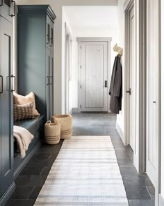 a hallway with gray walls and white trim, black tile flooring and grey cabinets