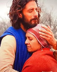 a man and woman embracing each other with trees in the background