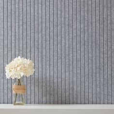 a vase filled with white flowers sitting on top of a table next to a wall