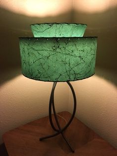 a green lamp sitting on top of a wooden table