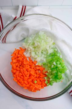 chopped carrots, celery and onions in a glass bowl on a counter