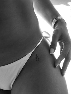 a woman's stomach with a small tattoo on her left side, and the lower part of her belly visible