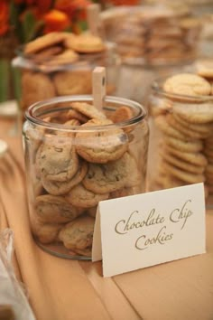 there is a jar full of cookies and a sign on the table that says chocolate chip cookies