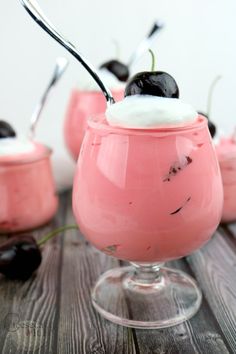 small desserts with cherries and whipped cream on top are sitting on a wooden table