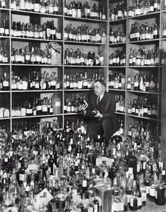 an old photo of a man in a room full of bottles