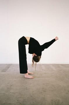 a woman doing a handstand on the floor in front of a white wall