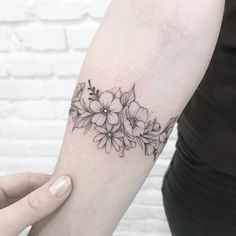 a black and white flower tattoo on the left inner arm, with flowers in it