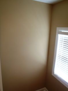 the corner of a room with a window and carpet on the floor in front of it