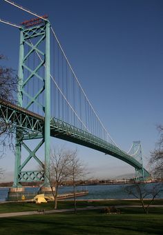 a large bridge spanning over a body of water with trees in the foreground and blue sky above