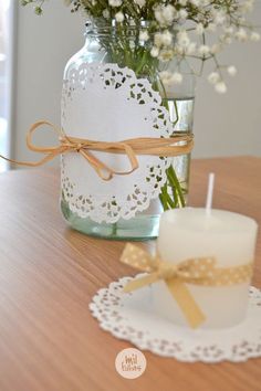 a vase with flowers in it sitting on a table next to a candle and doily