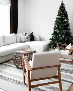 Celebrate the season with a life-sized Christmas tree in the corner of this monochrome living room. The white sofa blends in with the matching walls and lightly patterned rug on the floor below. Furnish the space with wood-framed armchairs and a rattan coffee table that add a hint of warm tones...   Image: homebodybrook