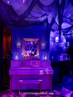 a room with purple lighting and a white piano in the center is decorated for halloween