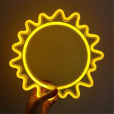 a person holding a yellow light up like a sunburst in the dark with their hand