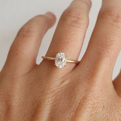 a woman's hand with a diamond ring on top of her finger, showing the center stone