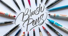 the words brush pens are arranged in a circle on a white surface with many different colored crayons