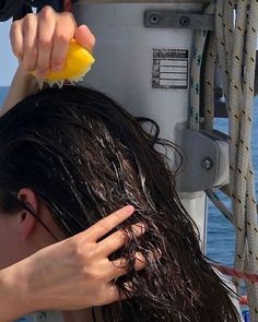 a woman is drying her hair on the deck of a boat in the ocean,