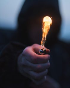 a person holding a lighter in their hand with the light shining on it's face