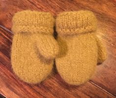 two yellow mittens sitting on top of a wooden table