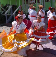 several women in colorful dresses are dancing outside