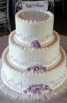 a three tiered wedding cake with purple flowers