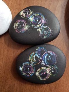 two black rocks with colorful bubbles painted on them