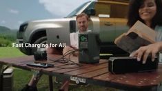 a man and woman sitting at a picnic table with their laptops in front of them