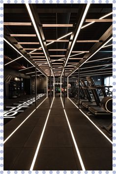 an indoor gym with rows of treadmills and lights