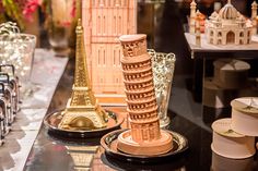 a table topped with lots of different types of vases and other decorative items in front of a clock tower