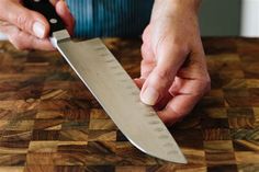 a person holding a knife on top of a wooden table