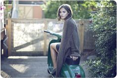 a woman sitting on the back of a moped