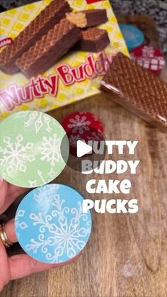 a person holding some candy in their hand with the words nutty buddy cake picks on it