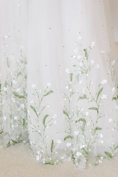 two white curtains with green and white flowers on them