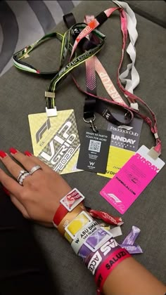 a woman's hand with two wristbands and several lanyards around her