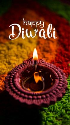 happy diwali greeting card with colorful background and lit candle on the ground in front of it