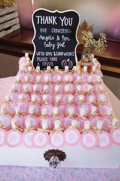 a pink and white cake with lots of cupcakes on it