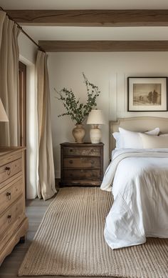 Antique dresser and bed in modern French country bedroom. This modern French country bedroom combines rustic charm with elegant simplicity. The focal point is a vintage-inspired iron bed frame, dressed in crisp white linens and adorned with soft, pastel throw pillows. The walls are a muted, neutral beige, providing a calm and cozy atmosphere. A distressed wooden nightstand holds a simple lamp and a few cherished books, adding a touch of rustic warmth. The floor is covered with a plush area rug Neutral Country Bedroom, Master Bedrooms Vintage, Antique Master Bed, White Flooring Bedroom, Nancy Myers Homes Aesthetic Bedroom, Linen Bed Frame Bedroom Ideas, Rustic White Bedroom Ideas, Country Style Home Interior, Simple Beige Bedroom