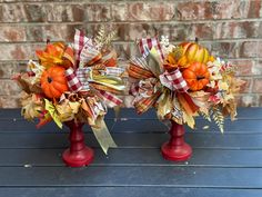 two red vases with fall decorations on them