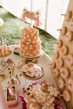 a table topped with lots of donuts and cake next to a tented area