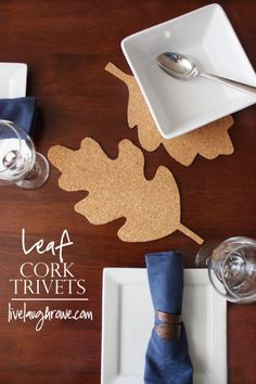 a place setting with napkins, silverware and cork leaves on the table top