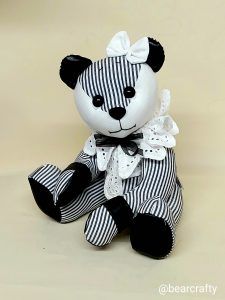 a black and white striped teddy bear with a bow on it's head sitting down