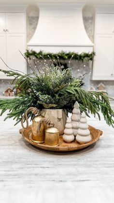 a christmas centerpiece with evergreen, pine cones and gold ornaments on a wooden tray