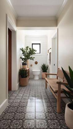 a white toilet sitting next to a wooden bench in a bathroom with potted plants