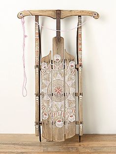 a wooden sled with an intricate design on the front and sides, hanging from a rope